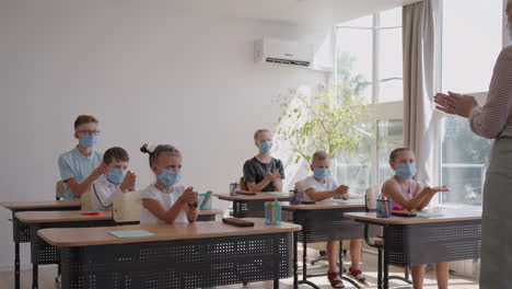 The-teacher-shows-the-children-the-rules-of-personal-hygiene-how-to-wash-their-hands-how-to-treat-their-hands-with-antiseptic.-how-to-use-a-sanitizer.-At-school-in-protective-masks